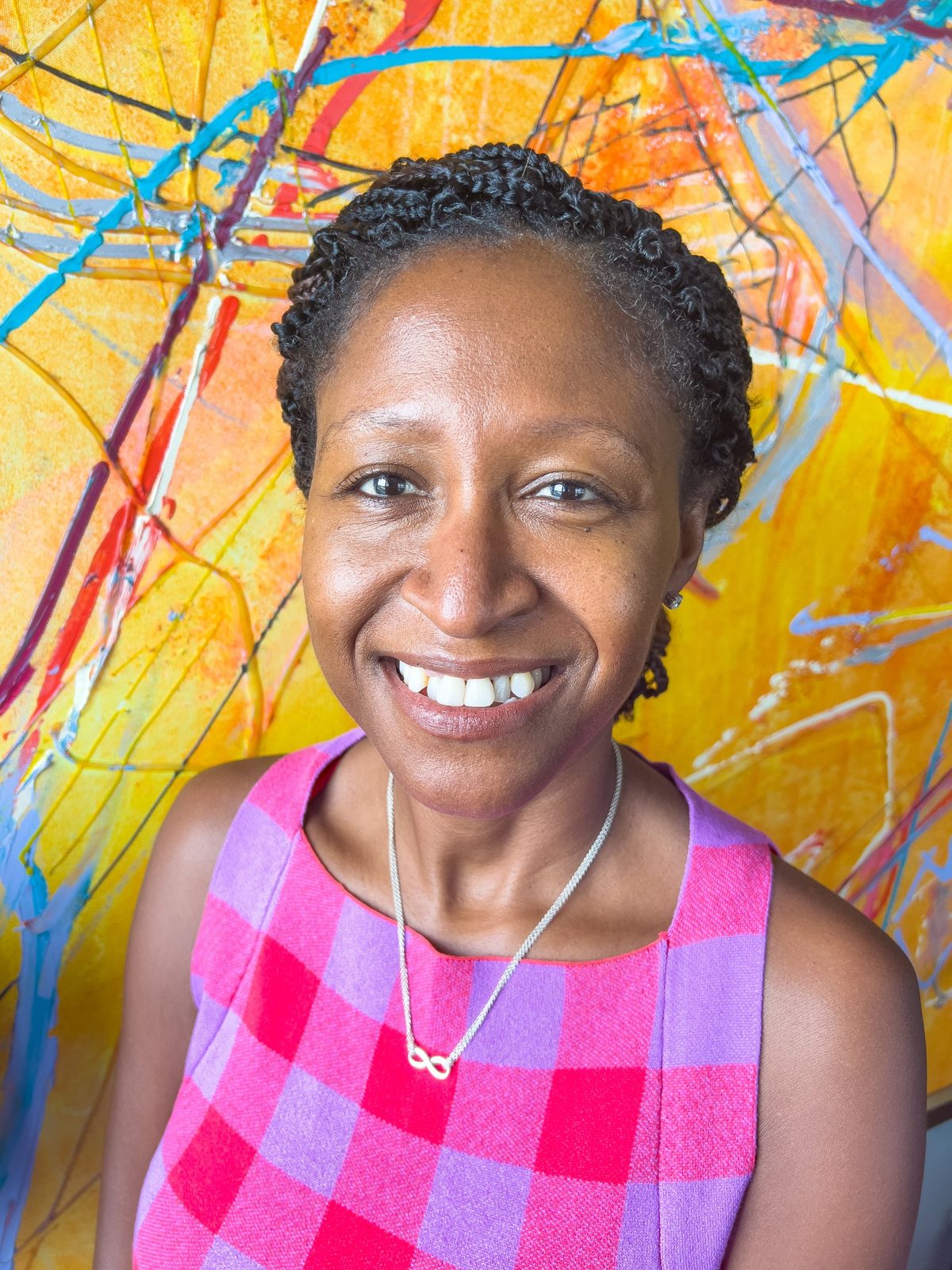 Darline Lalanne smiling in front of a bright orange abstract painting